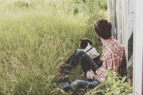 Man sitting in long grass with his dog, pet cremation in Sydney by Pet Memorial Australia